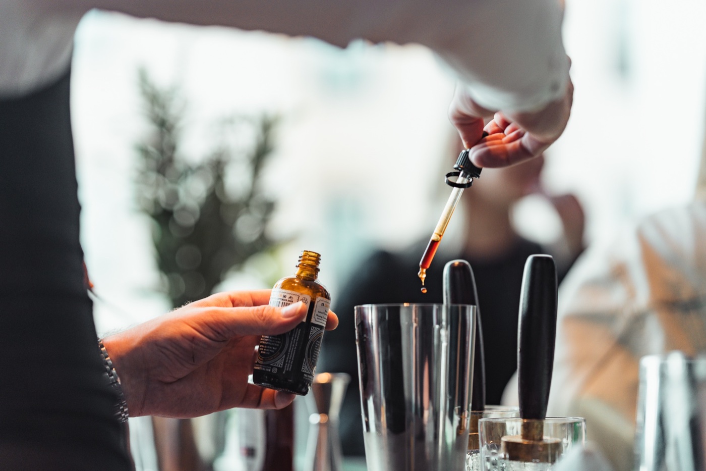 A bartender carefully adding bitters with a pipette while preparing a cocktail